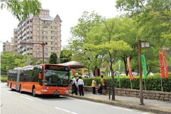 鮮やかなオレンジ色のバスが町中を走っている写真