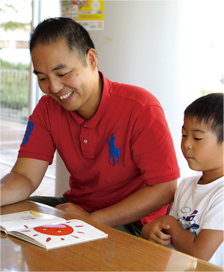 尾崎さんと子どもが絵本を読んでいる写真