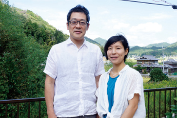 三田市の自然を背景に二人並ぶ椎木 康雄（しいき やすお）さんと妻の女性の写真