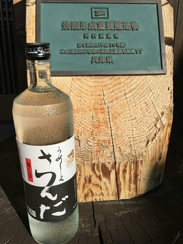 切り株と三田の地酒のボトルの写真