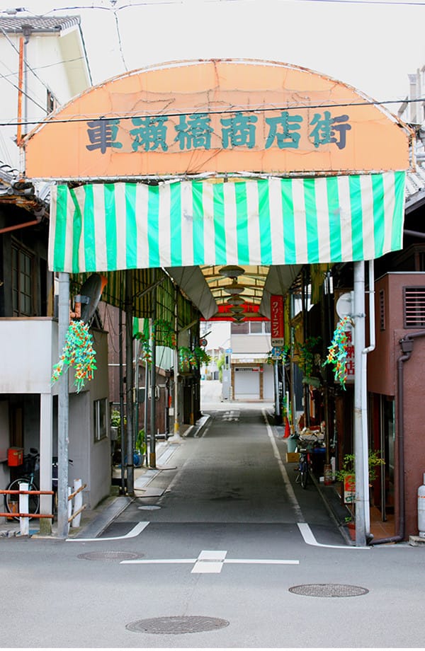 緑と白の縞模様の幕が張られた商店街の入口の写真