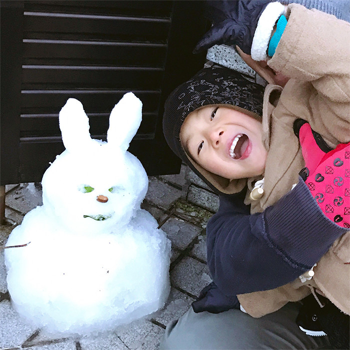 ウサギを模した雪だるまとその隣りで微笑む男子児童の写真
