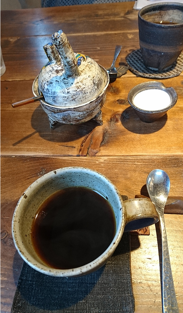 コーヒーポットとコーヒーが入ったお茶碗とミルクの写真